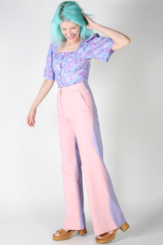 Woman wearing pink and purple wavy side seam Grass Owl pants by Birds of North America. 
