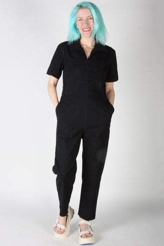 Woman wears black zip up Nonpareil boilersuit by Birds of North America. 