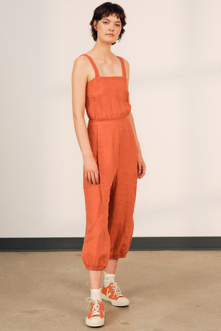 Model wearing pumpkin orange OEKO-TEK linen Danu jumpsuit by Jennifer Glasgow. 