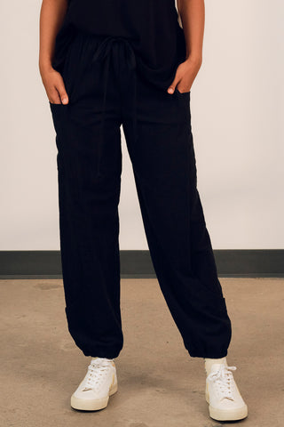 Close-up of model wearing black cotton track inspired Finnely Pants by Jennifer Glasgow. 