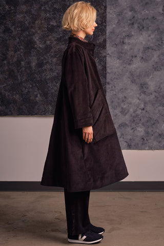 Side view of model wearing black corduroy A-line Joan coat by Jennifer Glasgow. 