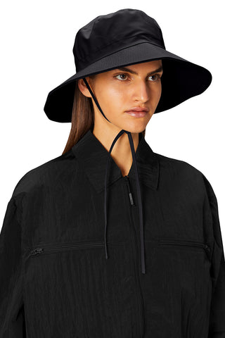Woman wearing black waterproof Boonie Hat by RAINS.