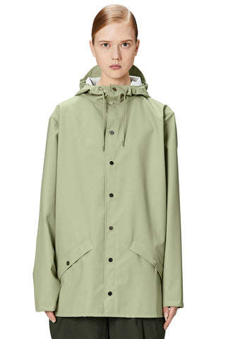 Woman wearing light  green waterproof rain jacket W3 by Rains.