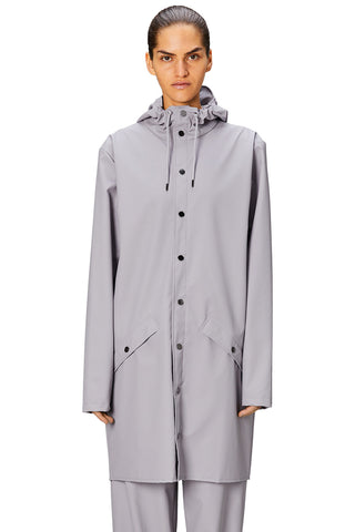 Woman wearing grey flint coloured waterproof Long Jacket by Rains. 