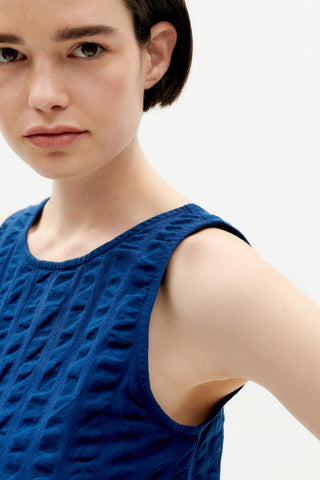 Closeup of woman wearing navy organic cotton Eda top by Thinking Mu. 