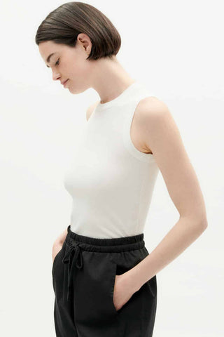 Woman wearing white organic cotton Juliette tank top by Thinking Mu. 