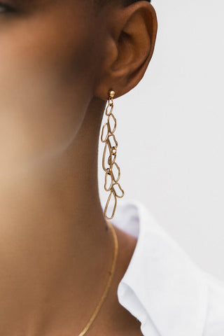 Model wearing Tilly Doro Long Moss gold plated earrings. 