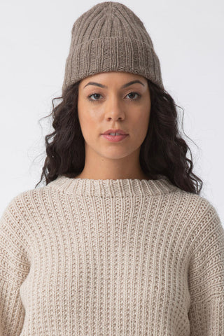 Model wearing oat brown thick knit yak wool hat by Dinadi. 
