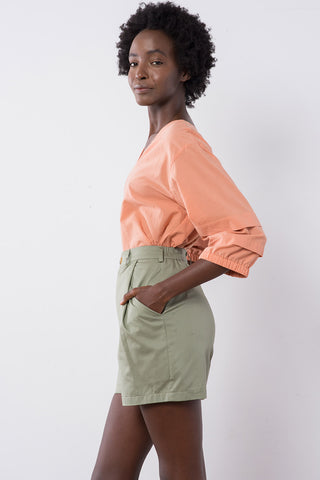 Model wearing sage organic cotton Jennifer Glasgow Charron shorts with pockets and elastic waist. 