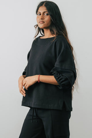 Model wearing black organic cotton Pearl Sweater with pleated sleeves by Jennifer Glasgow.