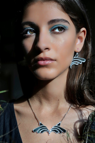 Woman wearing silver mirror effect plexiglass earrings and matching necklace. 