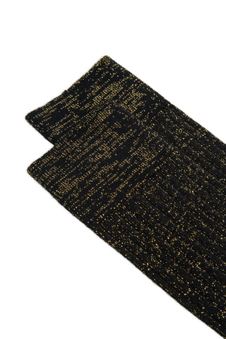 Close-up of a pair of black and gold lurex rib knit socks on white background. 