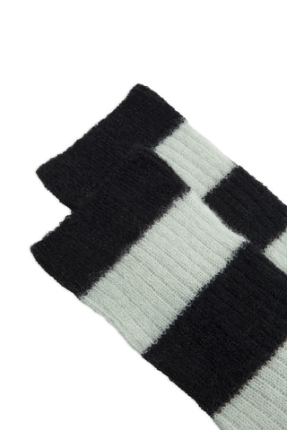Close-up of tops of black and white ribbed knit striped socks against white background. 