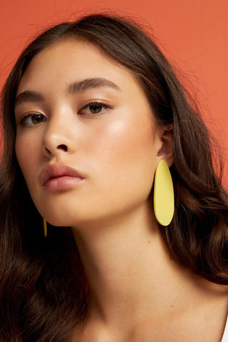 Woman wearing yellow polymer clay Ese X Apa earrings by Ade Studio. 