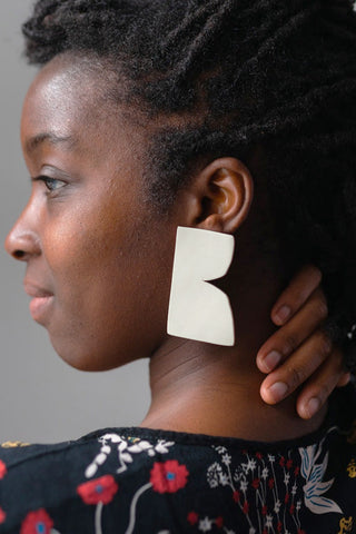 Model wearing cement polymer clay Igbaya Earrings by Adé Studio..
