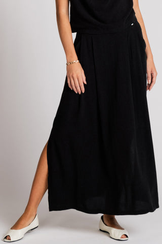 Woman wearing full length black skirt with side slit. 