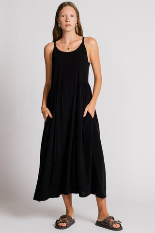 Woman wearing black maxi dress with drawstring waist and front pockets. 