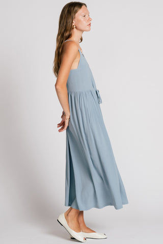 Side view of woman wearing light blue maxi dress with drawstring waist.
