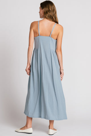 Back view of woman wearing light blue maxi dress with spaghetti straps. 