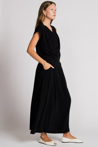 Side view of woman wearing  black tank top and black maxi skirt. 