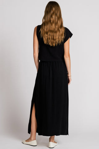 Back view of woman wearing lack tank top and black skirt with side slit. 