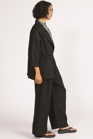 Side view of woman wearing loose fitting black linen Greer blazer by Allison Wonderland. 