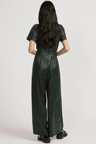 Back view of model wearing black shiny wide leg Spirited Jumpsuit by Allison Wonderland. 