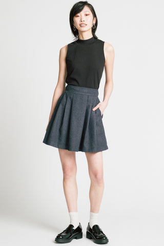 Woman in front of grey background wearing black tank top with grey pinstripe Trouble mini skirt by Allison Wonderland. 
