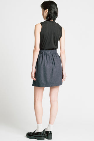 Back view of woman in front of grey background wearing black tank top with grey pinstripe Trouble mini skirt by Allison Wonderland. 