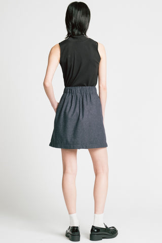 Back view of woman in front of grey background wearing black tank top with grey pinstripe Trouble mini skirt by Allison Wonderland. 