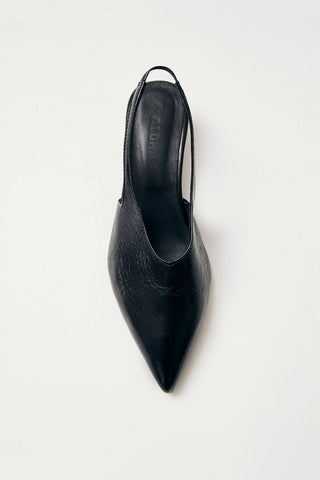 Top down view of black leather kitten heel sling back pumps on white background. 