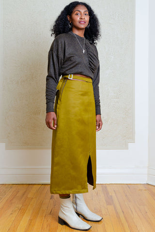 Woman standing in front of wallpapered wall wearing dark grey shirt and green A-line midi length Carmine Skirt by Andrea G. 