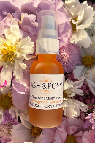 Ash Posy Cleaner Moisturizer in bed of flowers. 