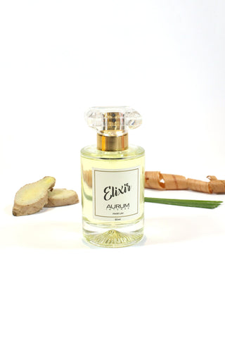 Bottle of Aurum Elixir perfume in front of white background with ginger, lemongrass and wood. 