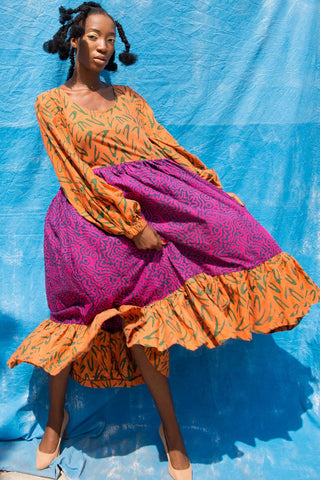 Woman wearing orange and pink batik print Osu Maxi Dress by Batik Boutik. 