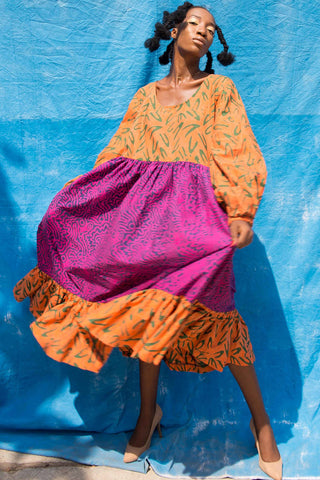 Woman wearing orange and pink batik print Osu Maxi Dress by Batik Boutik.