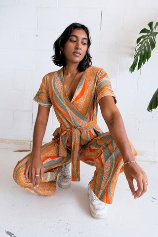 Woman wearing orange wax print Teshie Jumpsuit by Batik Boutik. 