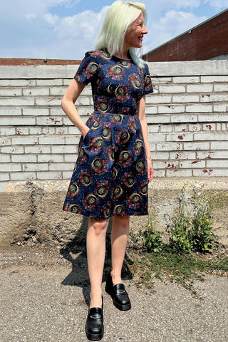 Model standing outside in front of brick wall wearing navy night owl print Buttonquail dress by Birds of North America. 