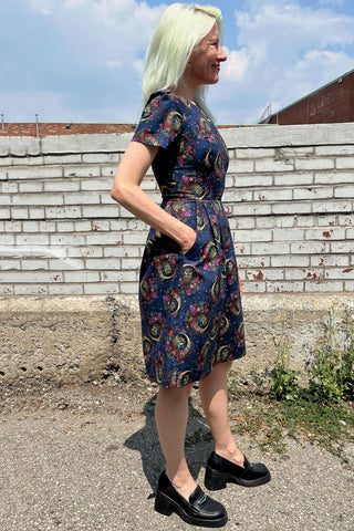 Model standing outside in front of brick wall wearing navy night owl print Buttonquail dress by Birds of North America. 