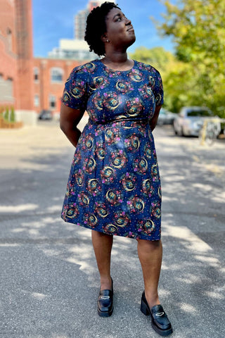 Model standing outside in parking lot wearing navy night owl print Buttonquail dress by Birds of North America. 