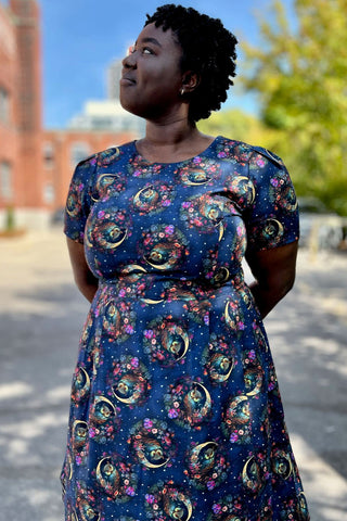 Model standing outside in parking lot wearing navy night owl print Buttonquail dress by Birds of North America. 