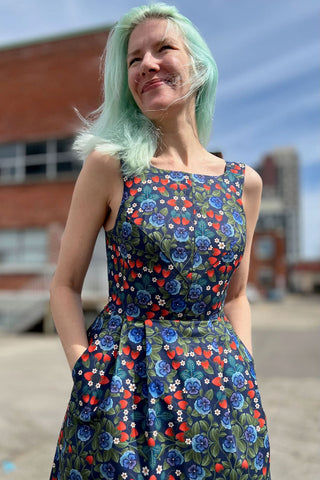 Woman outside wearing knee length sleeveless multi-colour floral dress. 