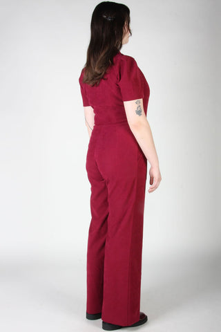 Back view of woman in front of grey background wearing mulberry zip up Tyrannulet jumpsuit by Birds of North America. 