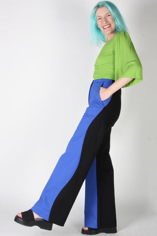 Woman wearing blue and black wavy side seam Grass Owl pants by Birds of North America. 