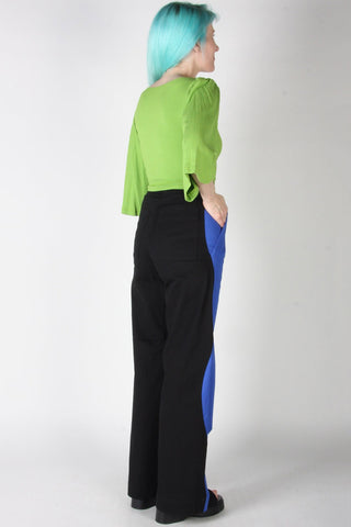 Woman wearing blue and black wavy side seam Grass Owl pants by Birds of North America. 