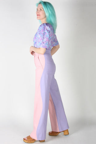 Woman wearing pink and purple wavy side seam Grass Owl pants by Birds of North America. 