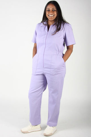 Woman wears lilac purple zip up Nonpareil boilersuit by Birds of North America. 