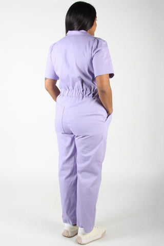 Back view of woman wears lilac purple zip up Nonpareil boilersuit by Birds of North America. 