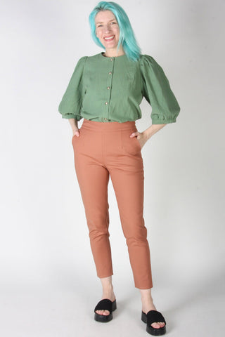 Woman wearing peach cropped tapered leg Tern pants by Birds of North America. 