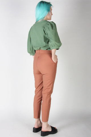 Back view of woman wearing peach cropped tapered leg Tern pants by Birds of North America. 